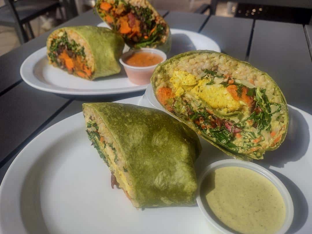 A wrap with rice, tofu scramble, and sweet potato. Served with pumpkin seed sauce.