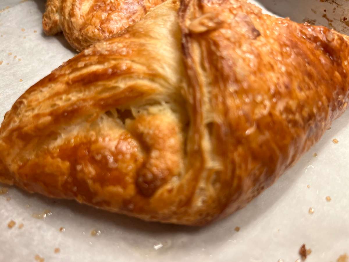 A golden, flaky pastry filled with savory ingredients is baked to perfection, featuring a crispy layered crust and rich homemade bakery appeal.
