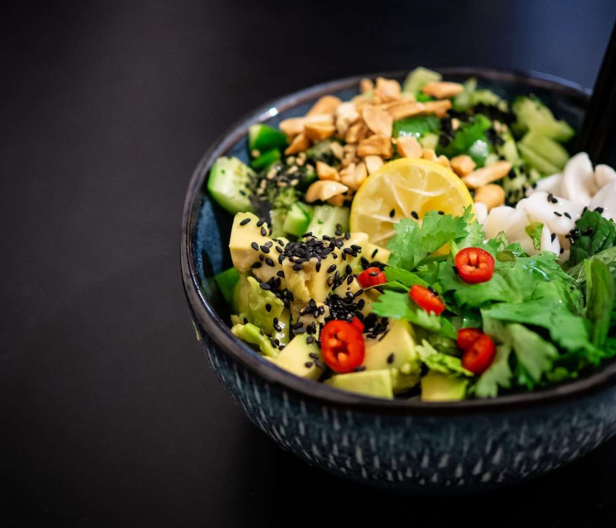 A fresh and colorful poke bowl topped with vegetables and seasoning