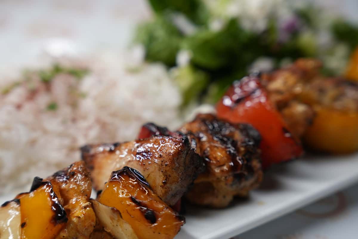 Chicken kebab skewer with a side of rice and salad