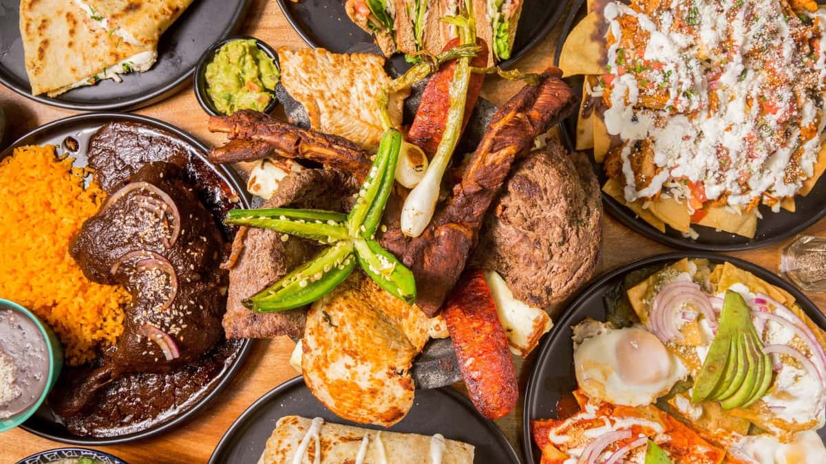 Mixed grill platter featuring steak, sausage, potatoes, and Mexican favorites.