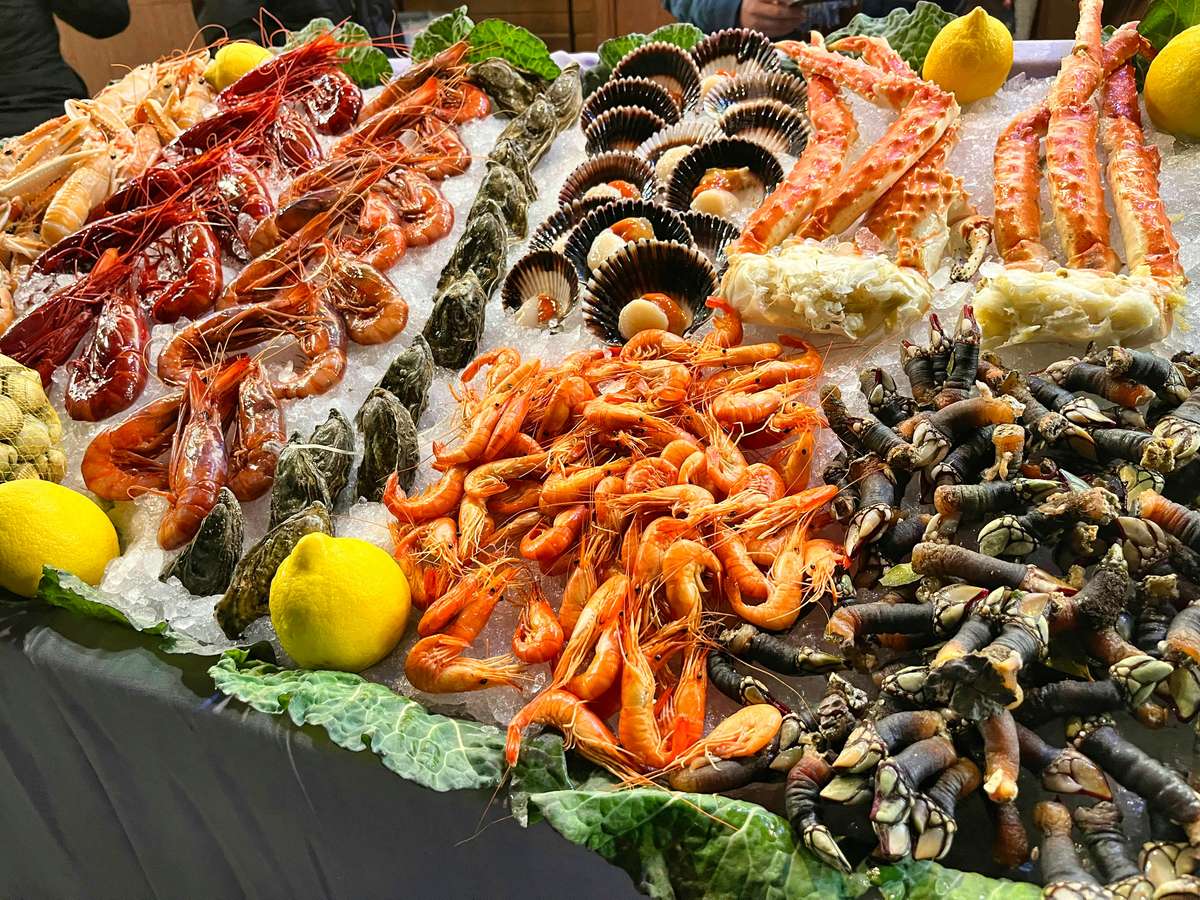 Colorful seafood display on ice with prawns, oysters, king crab legs, scallops, and lemons—ideal for a raw bar or upscale seafood buffet setting.