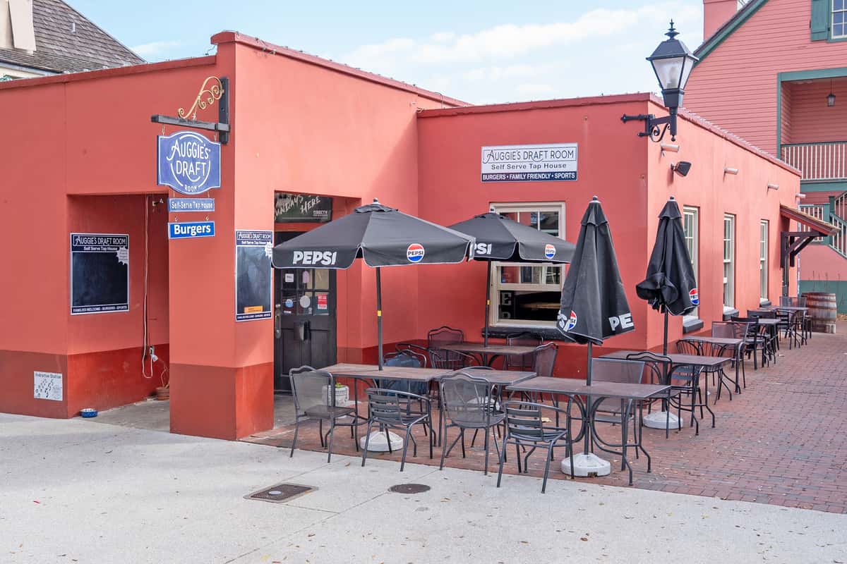 Auggie's Draft Room outdoor patio in downtown St. Augustine with umbrella-covered tables and casual seating outside the restaurant.