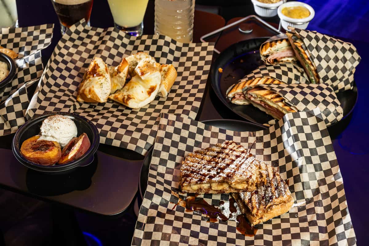 Multiple dishes on checkered paper available at The Riot