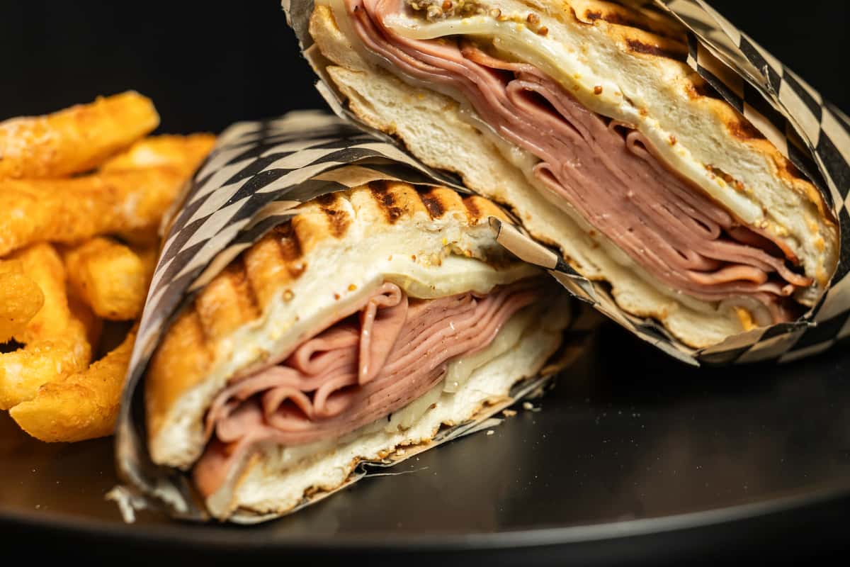 Italian Panini cut in half to show filling, wrapped in checkered paper