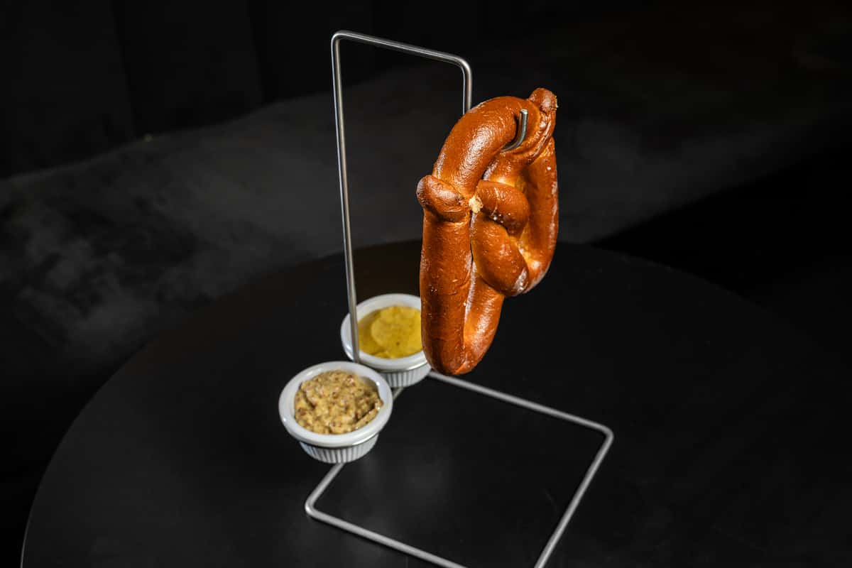 Pretzel hanging from hook with two dipping sauces