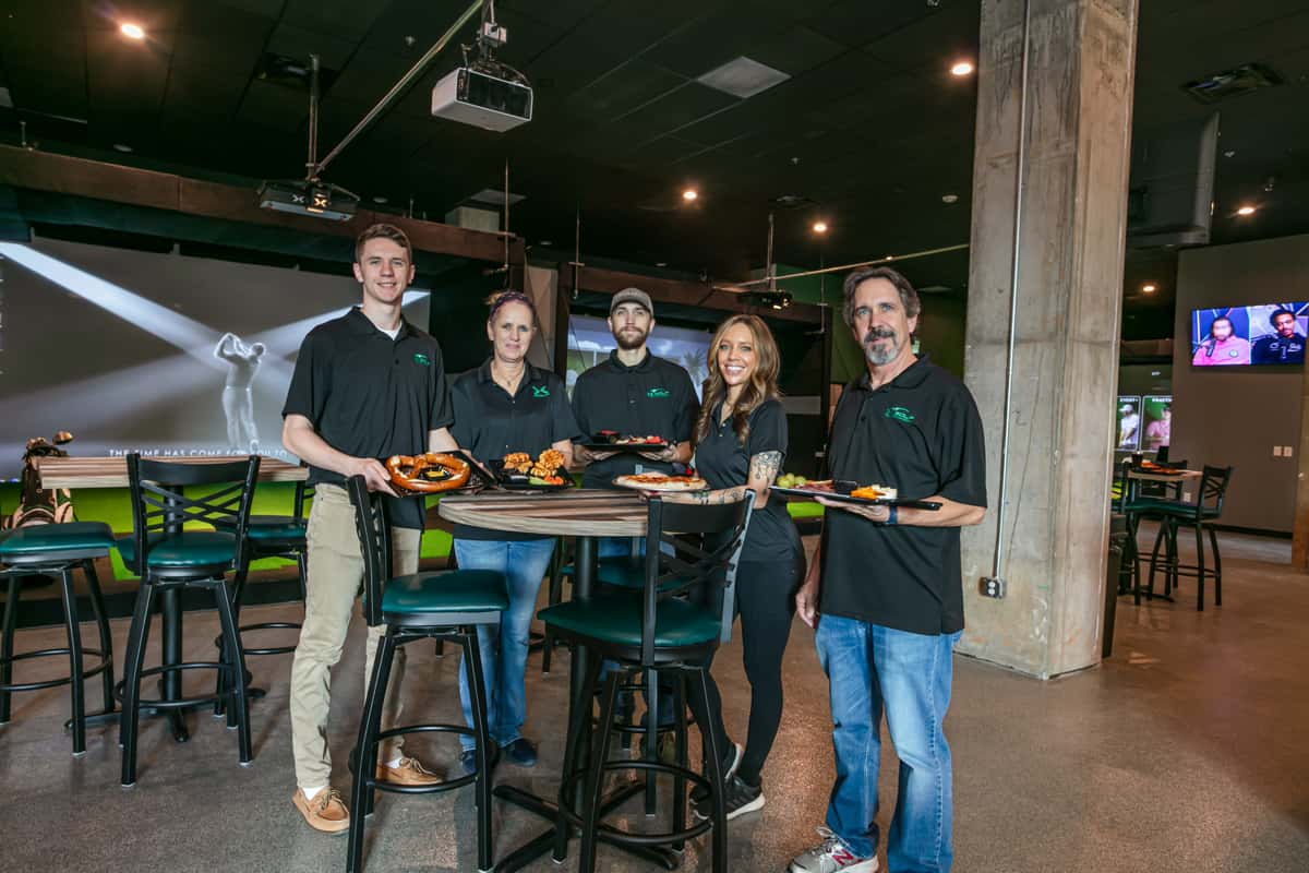 Staff members holding various food dishes