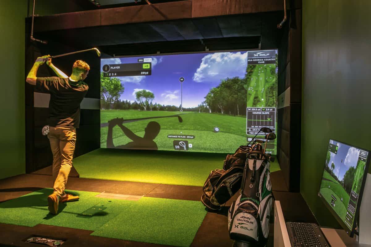 Player golfing in front of a simulator screen