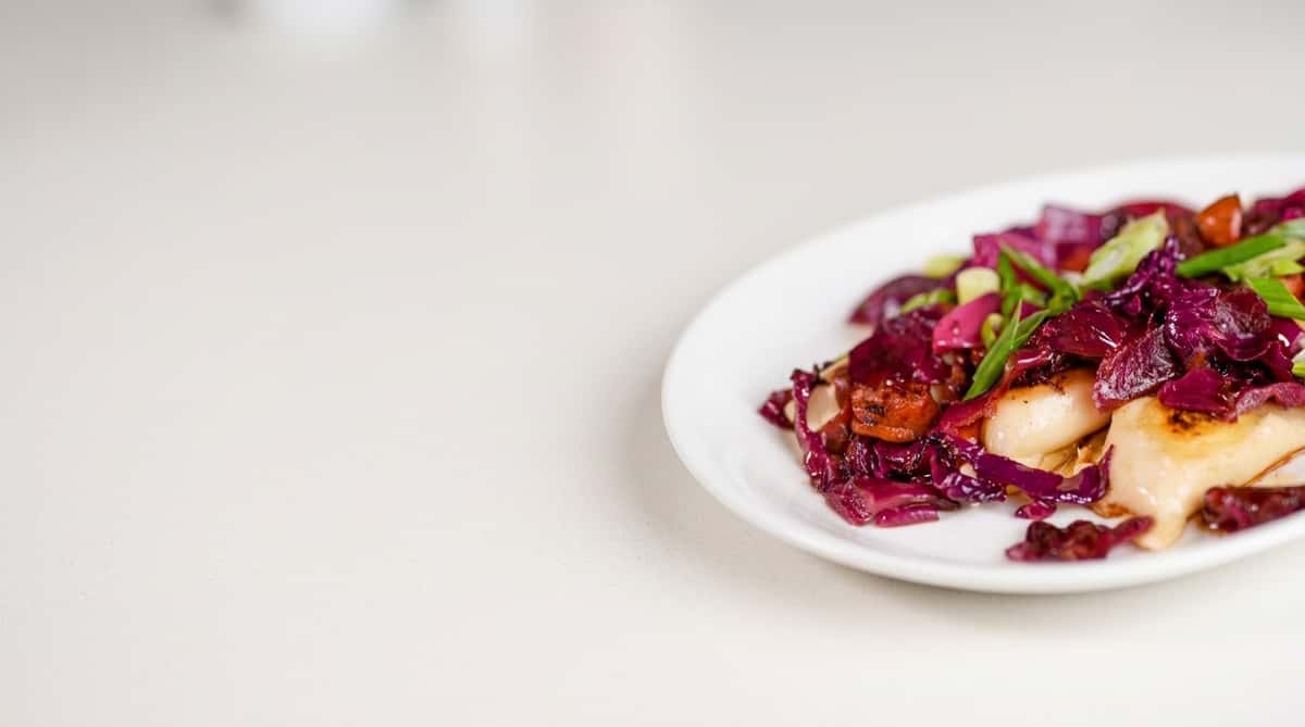 Seared scallops with braised red cabbage and roasted vegetables on a white plate at The Treehouse restaurant in Cleveland, Ohio.