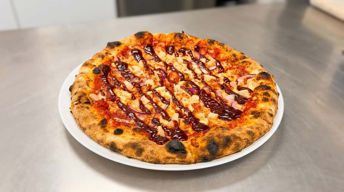 BBQ chicken pizza with diced chicken, red onions, mozzarella, and a generous drizzle of barbecue sauce.