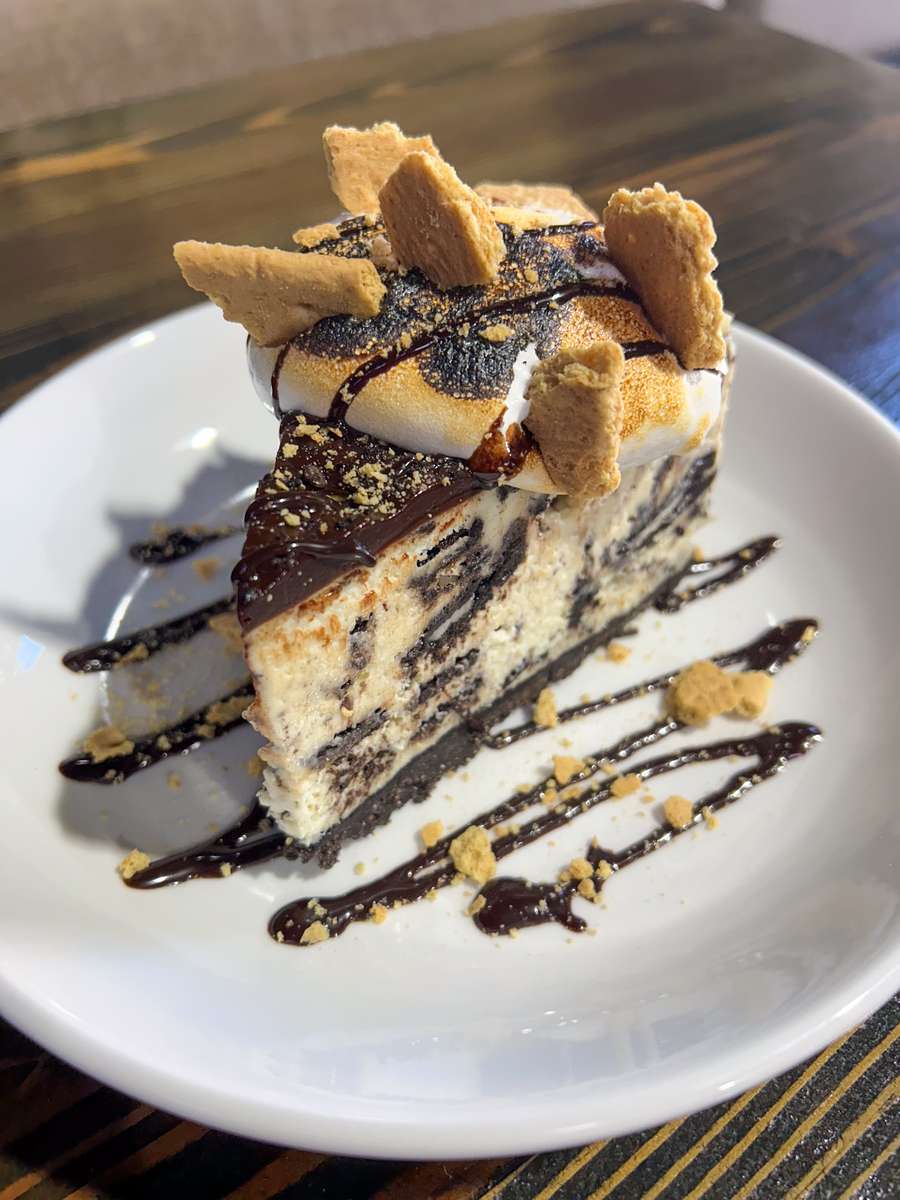 S'mores Oreo cheesecake topped with toasted marshmallow, chocolate sauce and crushed graham crackers