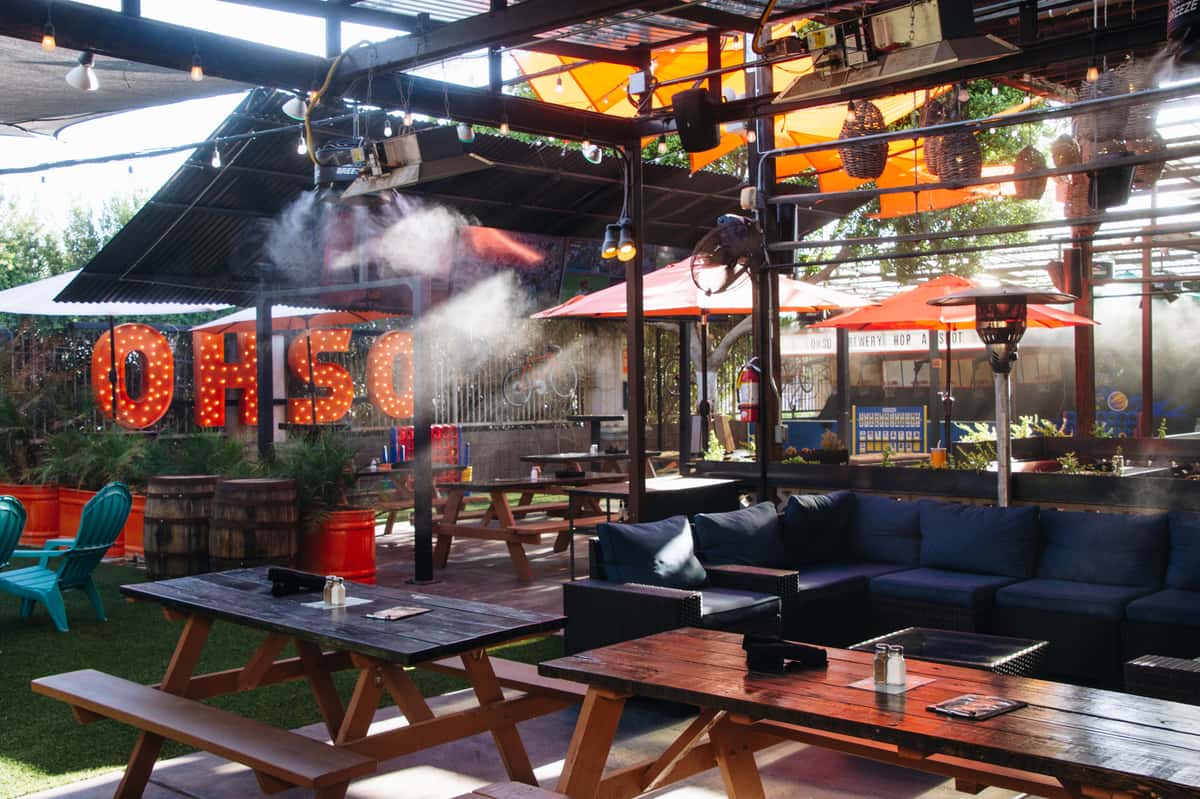 Paradise Valley patio at O.H.S.O. with big-screen TVs, shaded outdoor seating, misters, and lawn space for group events.
