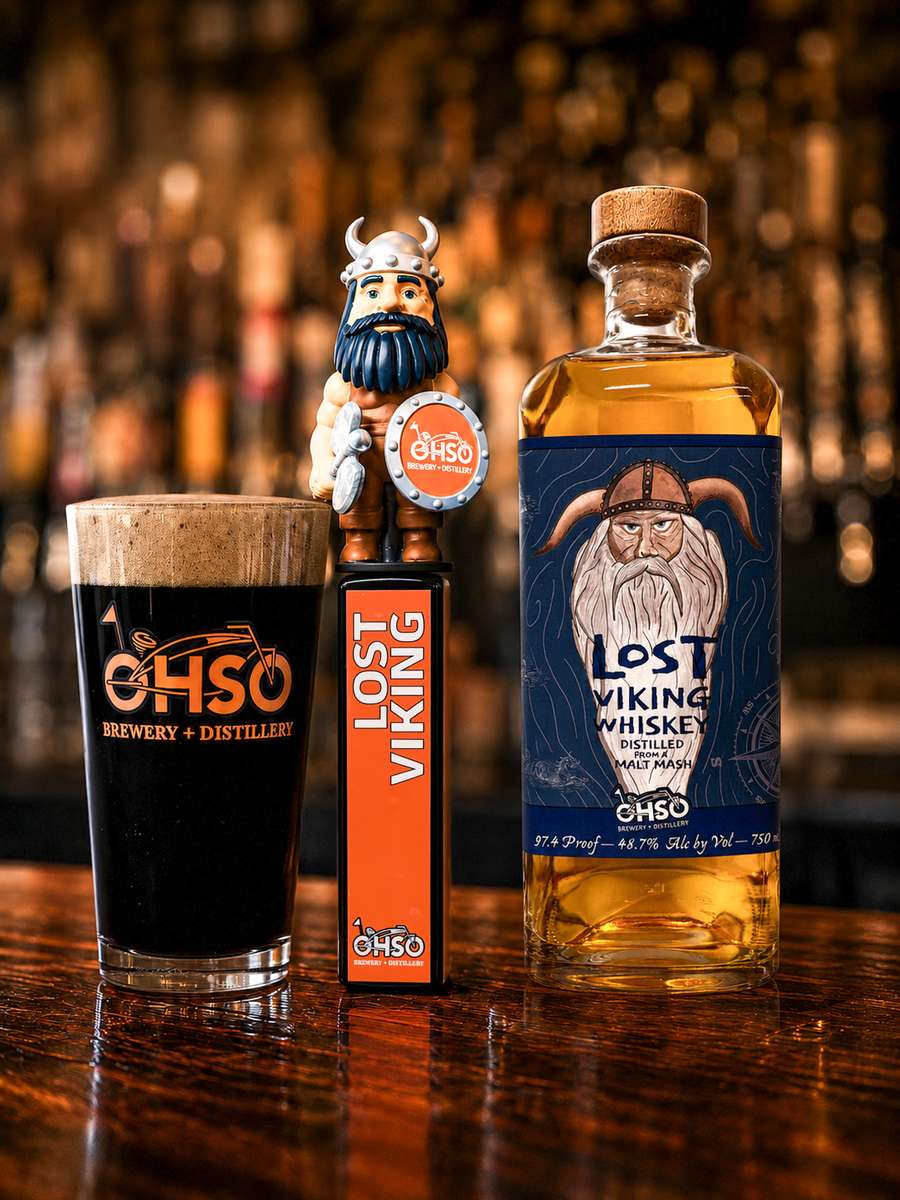 OHSO Pint glass of Lost Viking Baltic Porter next to Lost VIking Tap Handle and bottle of Lost Viking Whiskey.