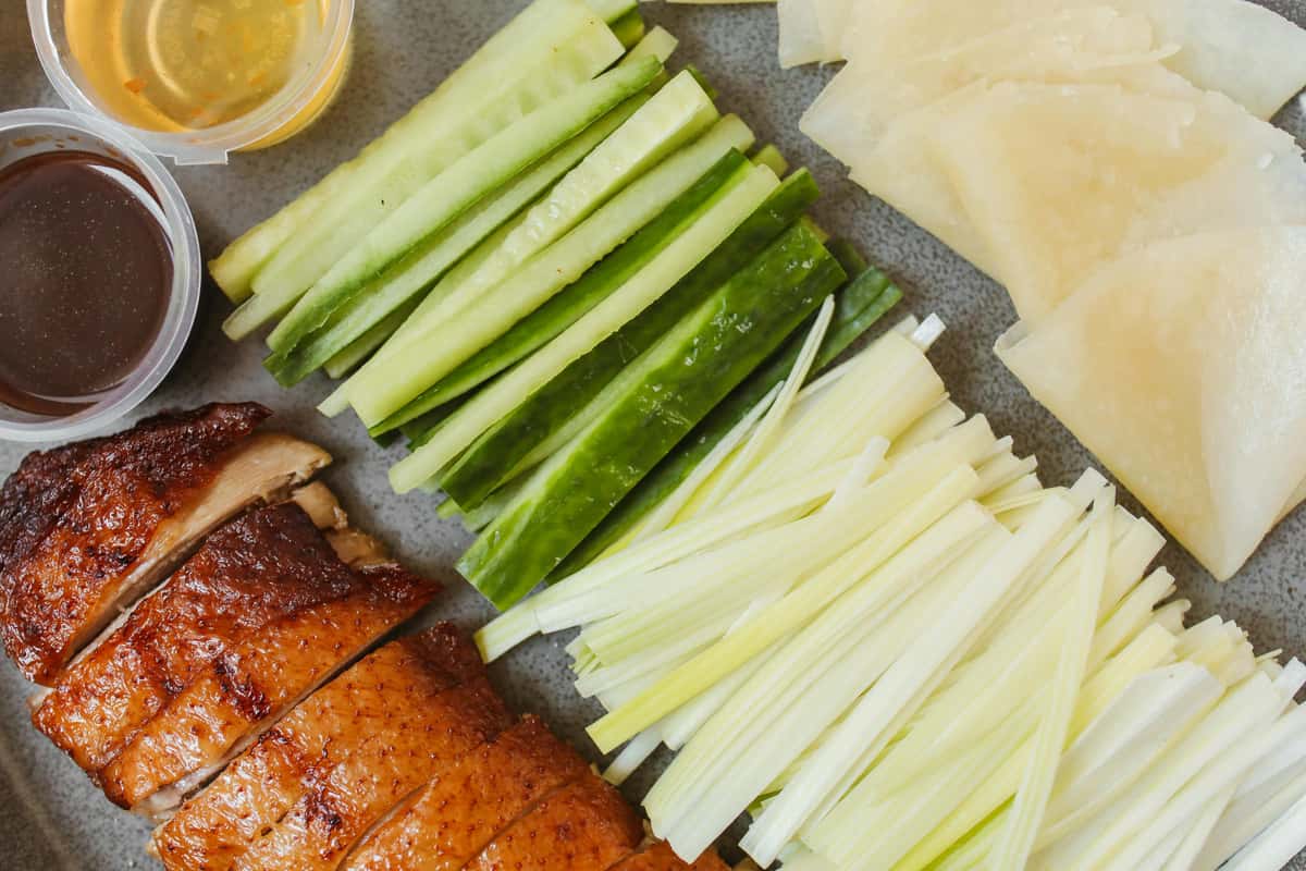 Top view of Peking duck with cucumber, onion, and sauces, ready to serve.