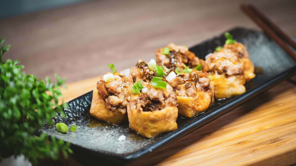 Savor delicious dim sum tofu garnished with green onions, captured in an elegant setting.