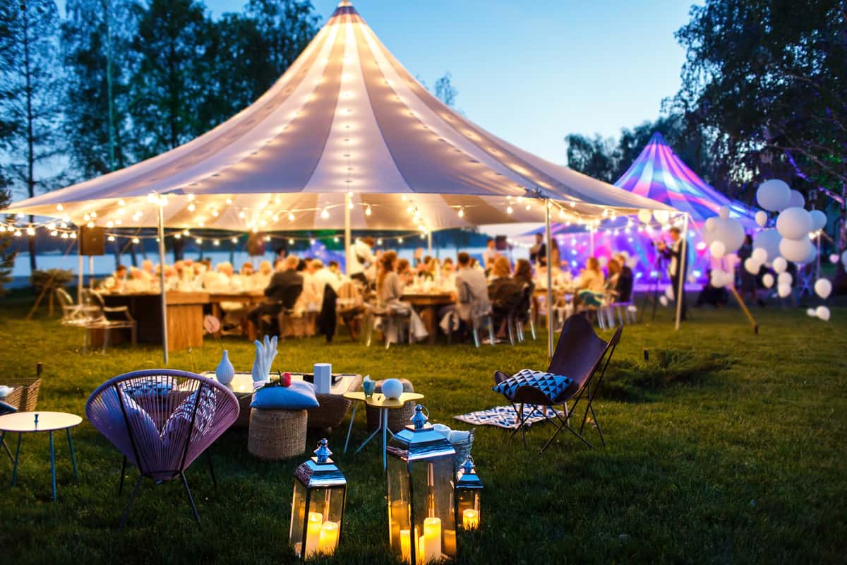 Event tent lit up with hanging lights outdoors at Dusk