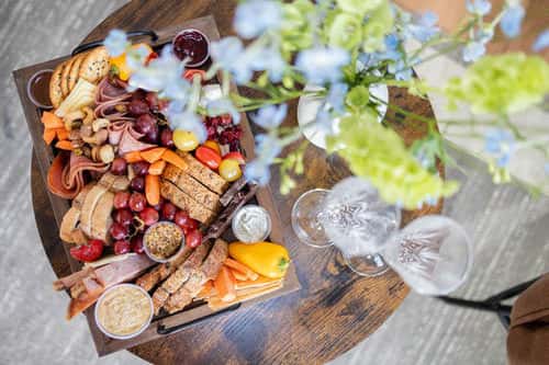 Charcuterie board with champagne glasses and fresh flowers