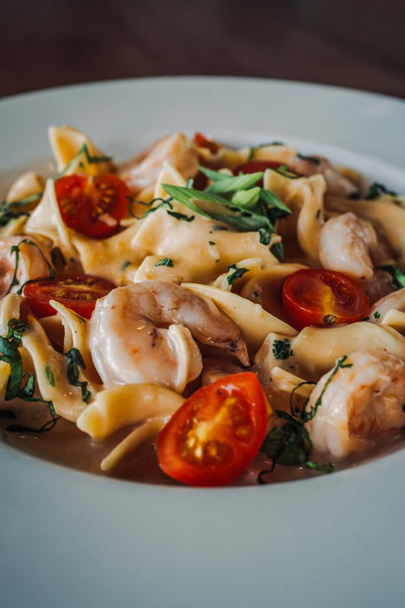 Creamy shrimp pasta tossed with sautéed shrimp, cherry tomatoes, and fresh herbs in a rich Alfredo-style sauce, served on a white plate.