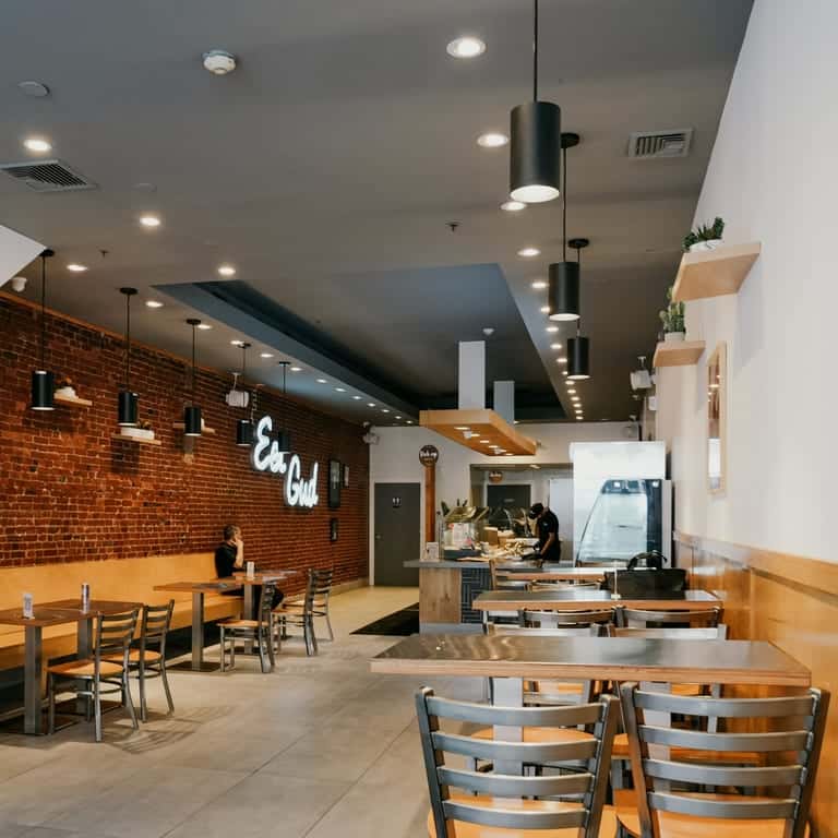 modern fast casual restaurant interior with wooden tables, brick accent walls, and open kitchen seating