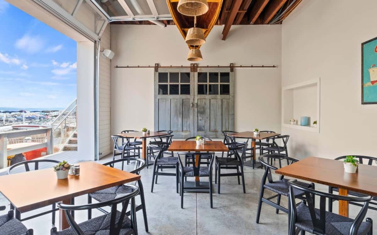 Restaurant patio seating area with wooden tables, chairs, and a city view