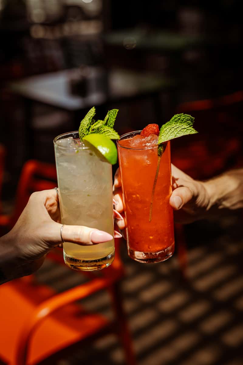 two customers clink mojito glasses