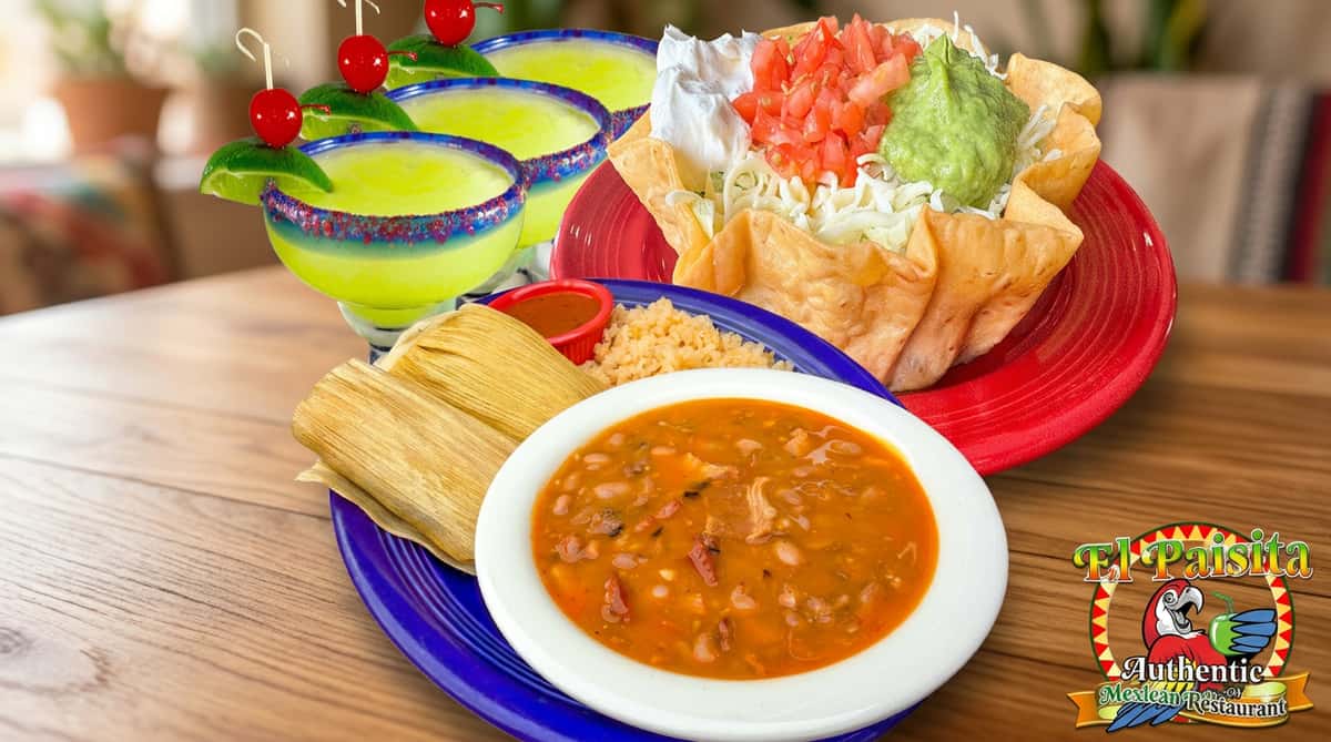Margaritas with lime and cherries, a taco salad bowl, a bowl of beans, tamales, and rice with El Paisita logo.