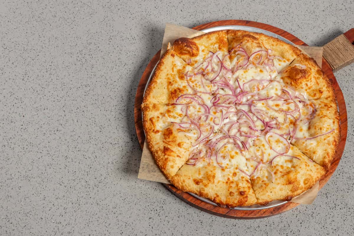 Freshly baked cheese pizza topped with thinly sliced red onions on a golden, bubbly crust, served on a round wooden board for a simple yet savory classic.