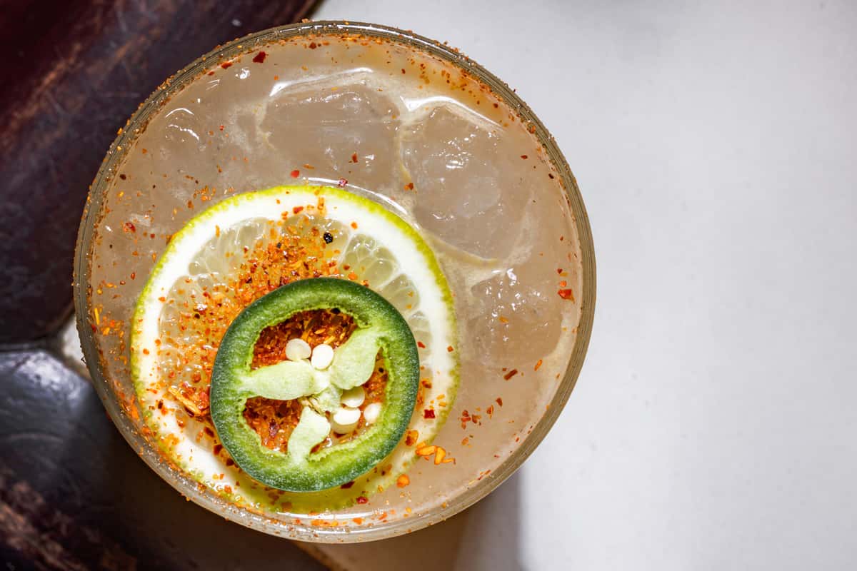 Freckled Mexican Martini with a lemon wedge, jalapeno and a sprinkle to tajin
