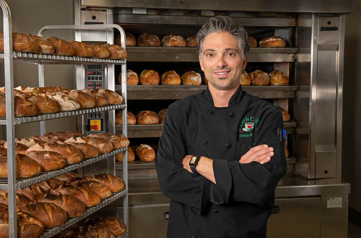 Chef Davide standing in front of just baked bread in Urth's kitchen