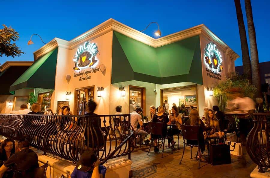 Exterior view of Urth Caffe Melrose with guests sitting at tables on patio
