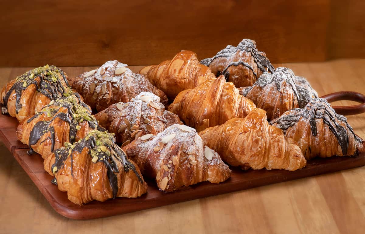 12 croissant on a wooden tray: chocolate pistachio, almond, plain and chocolate