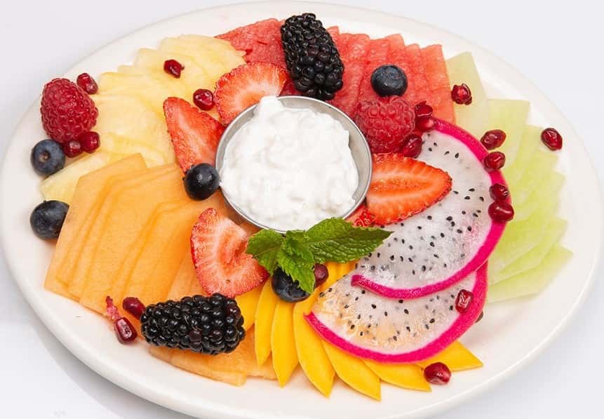 Fruit plate with sliced melon, dragon fruit, watermelon, strawberries and more