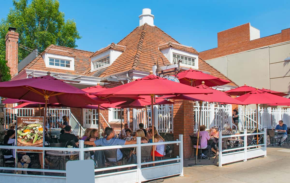 Exterior view of Urth Caffe Beverly Hills showing patio with guests sitting under red umbrellas