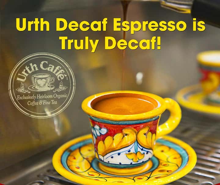 Colorful ceramic painted espresso cup and saucer with dark brown espresso dripping into a full cup.