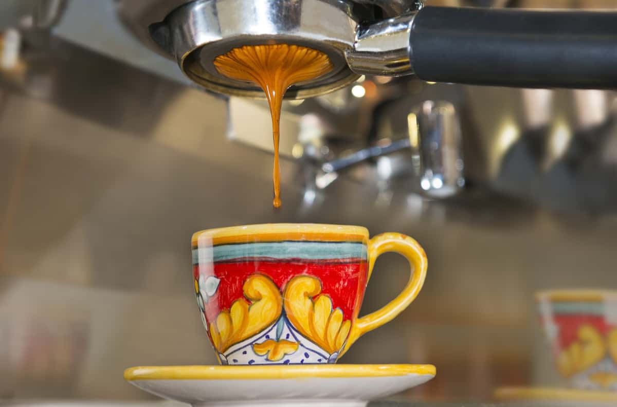 decorated espresso cup with espresso dripping into it