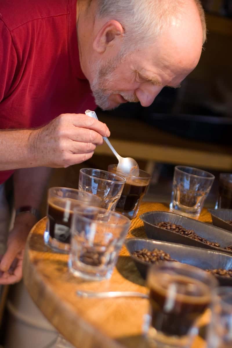 Man in red shirt "cups" the coffee to taste it