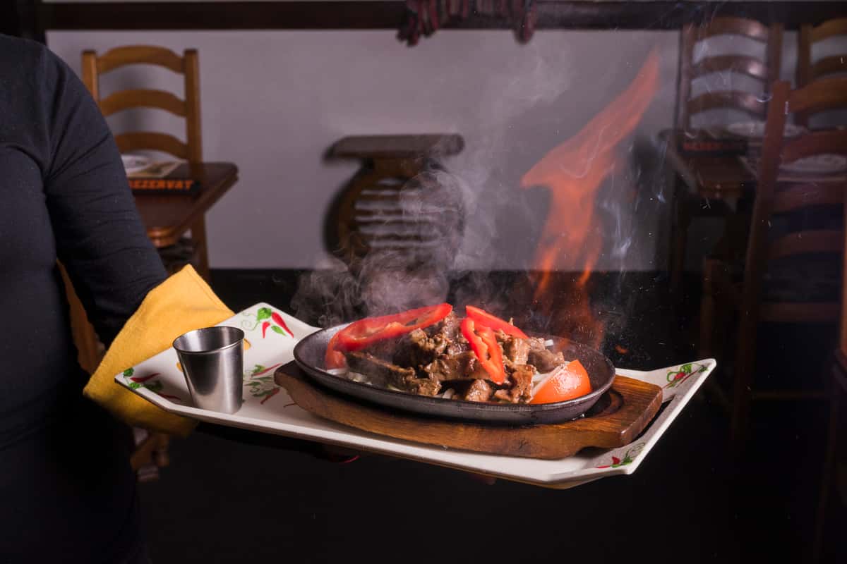 waiter carrying tray with meat fire