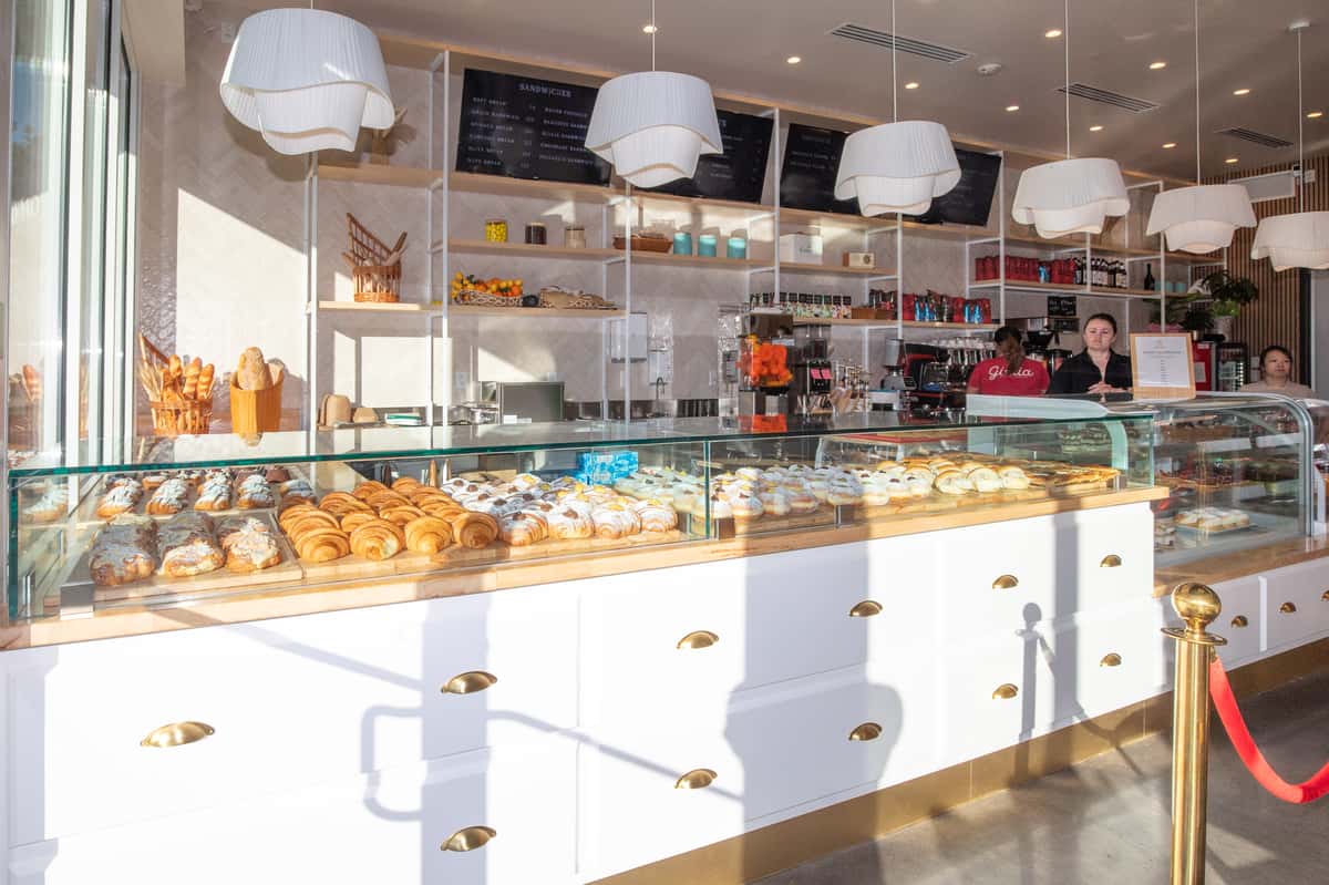 Glass display filled with pastries at Giulia Bakery, with a white counter, pendant lights, and open shelving behind it.