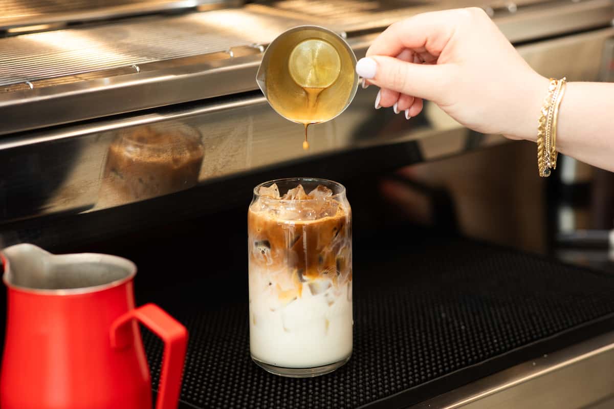 Espresso poured from a small cup into a glass of milk and ice at Giulia Bakery.