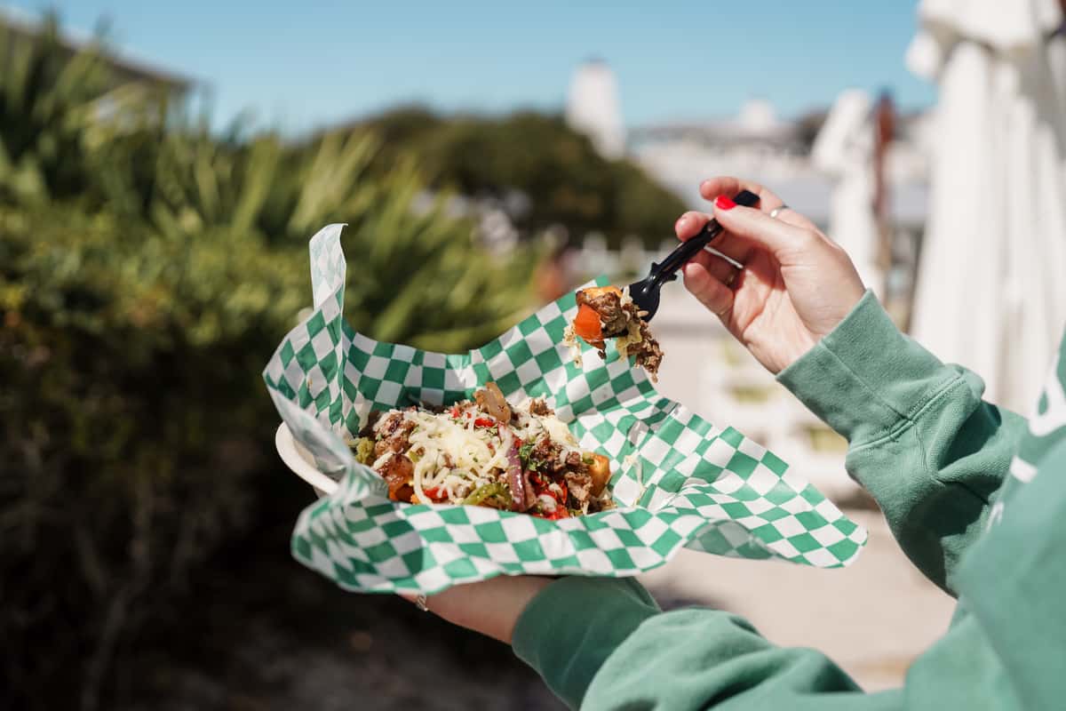 Outdoor seafood feast featuring fried shrimp, onion rings, sandwiches, sauces, and fresh sides at a coastal restaurant.