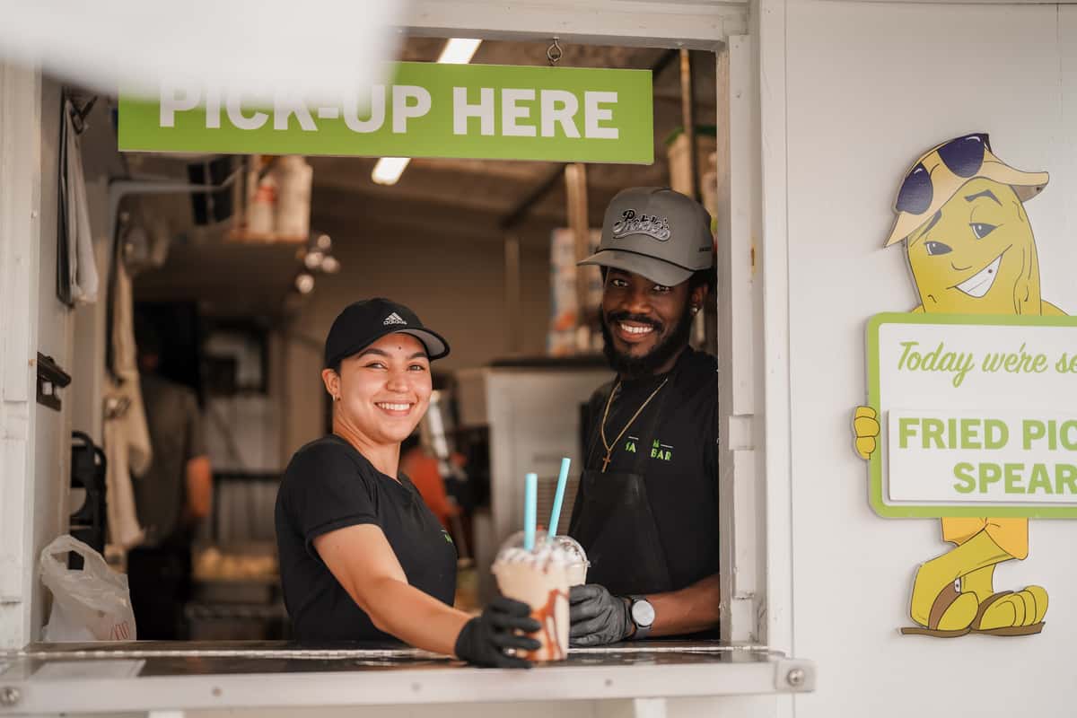 Restaurant team members smiling at a pickup window while serving refreshing drinks to guests.