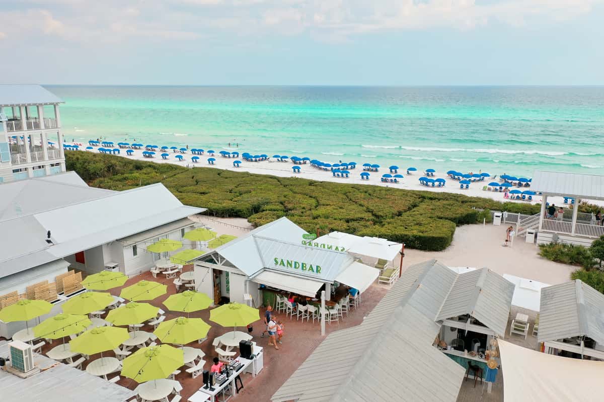Aerial view of a beachfront restaurant with outdoor seating overlooking white sand beaches and turquoise water.