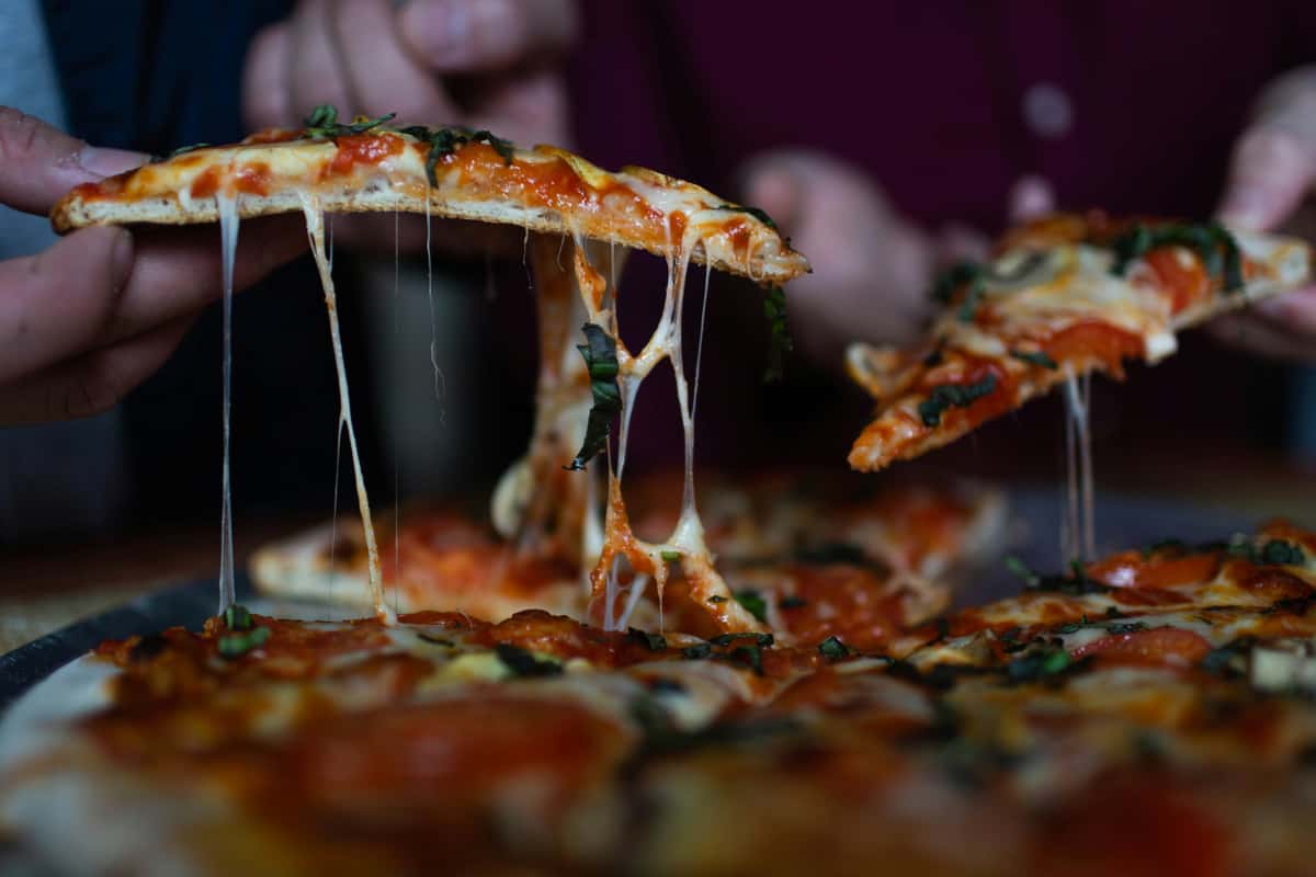 Close-up of a traditional Neapolitan Margherita pizza with charred crust, melted mozzarella, tomato sauce, and fresh basil on a marble surface.