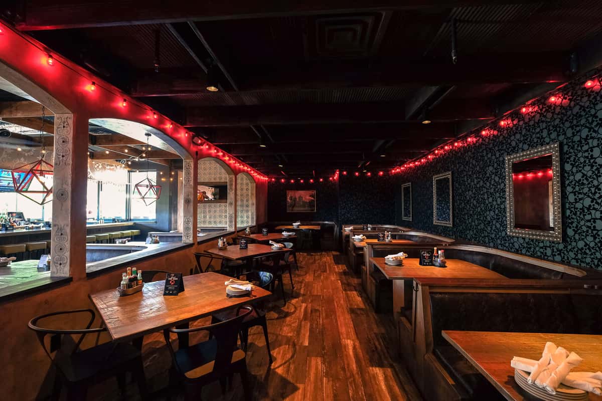 Large venue space for up to 350 people with booth and table seating, red string lighting and black grayscale skull wall paper pattern