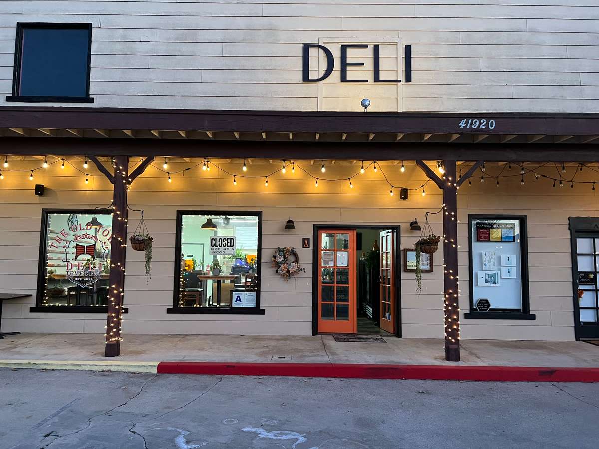 The entrance of The Old Town Deli, featuring an illuminated sign and decorative string lights.