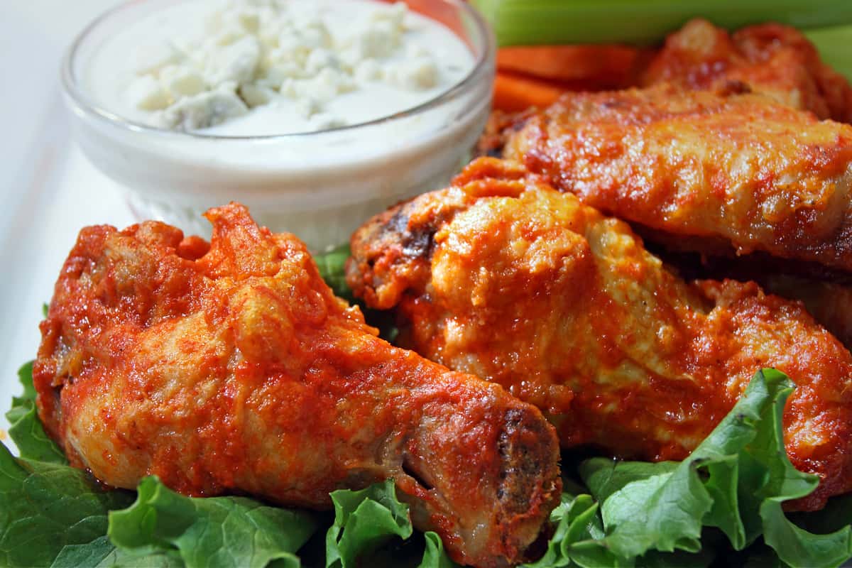 Buffalo wings over bed of lettuce next to cup of blue cheese