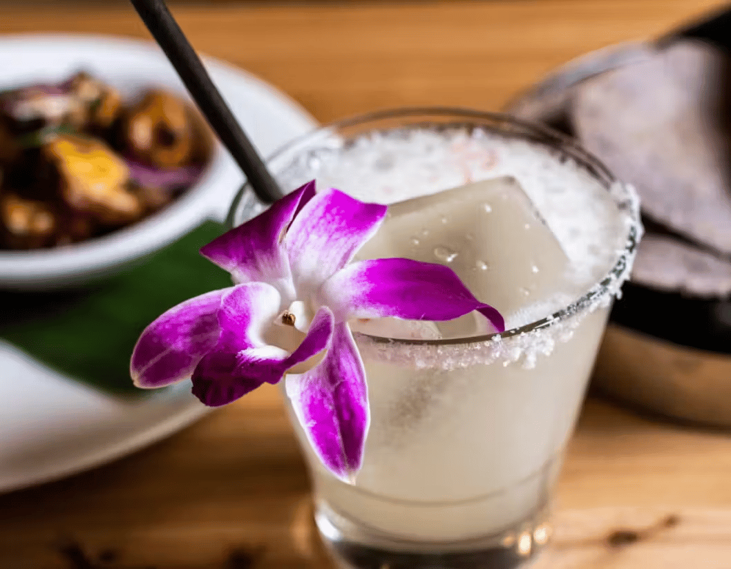 Handcrafted margarita garnished with a purple orchid, served at Hugo's restaurant with fresh Mexican cuisine.