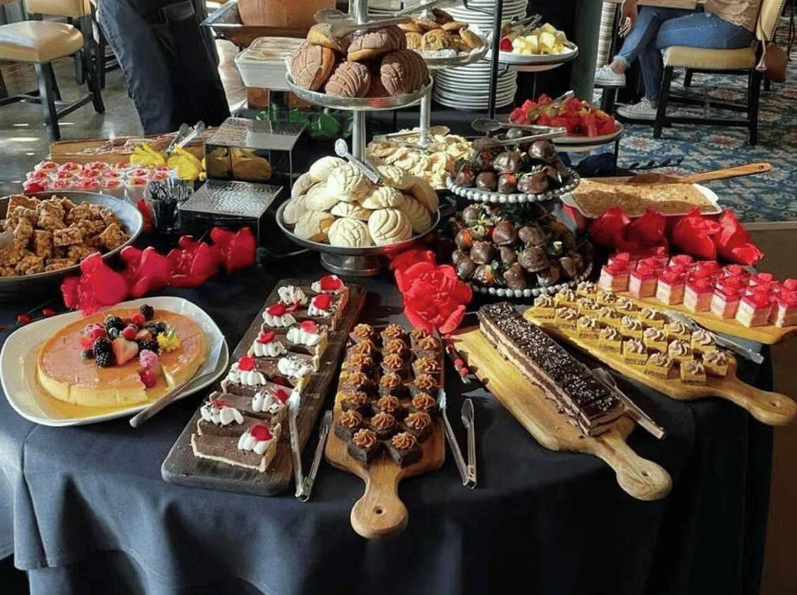Elegant brunch buffet featuring assorted desserts, pastries, fresh fruit, and breakfast favorites at Hugo's restaurant.