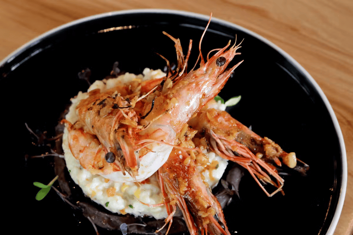 Creamy Mexican rice topped with whole grilled shrimp, served as a signature seafood entrée at Hugo's restaurant.