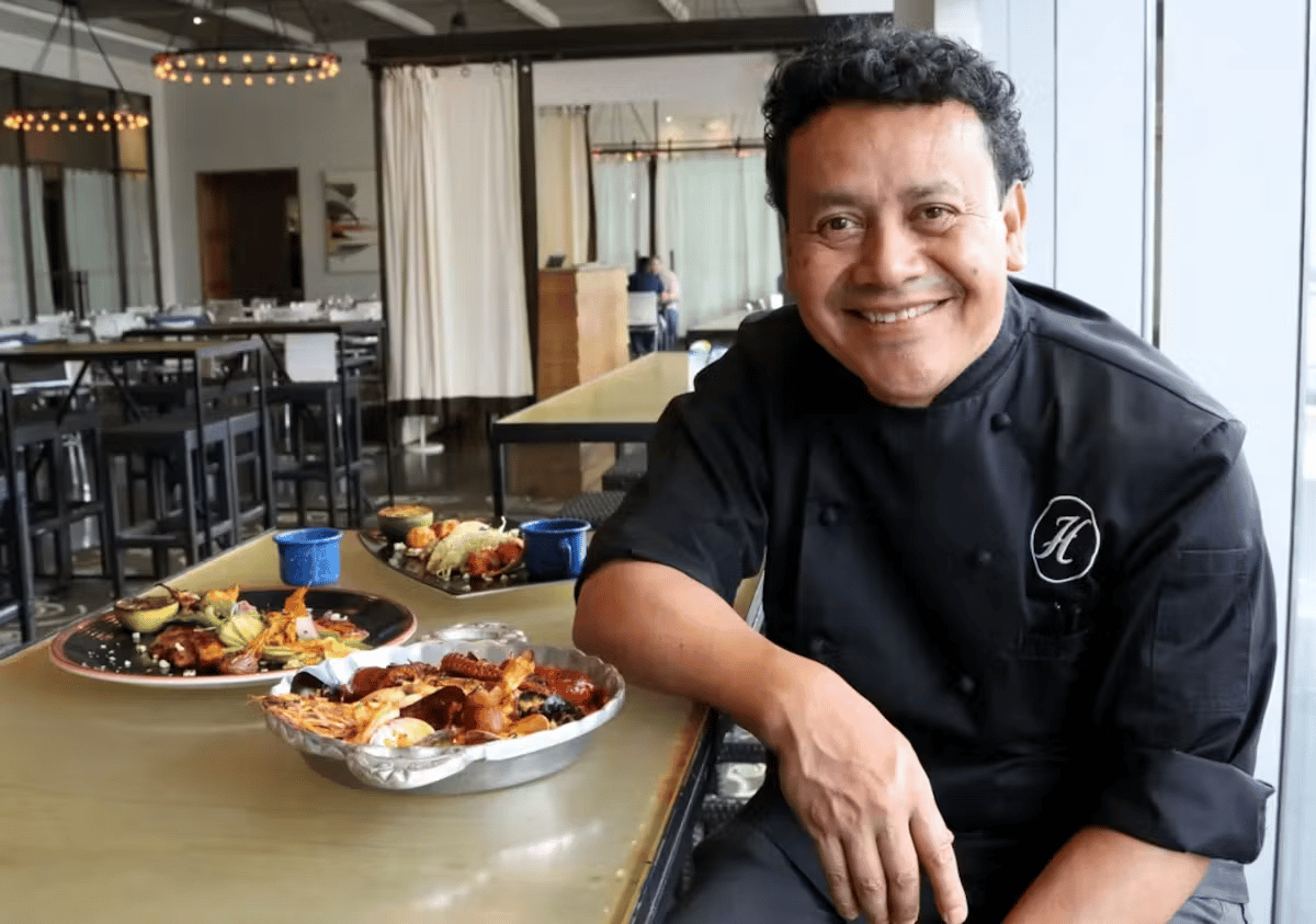 Chef Hugo smiling in the dining room while presenting signature Mexican dishes at Hugo's restaurant.